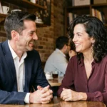 Couple élégant en conversation animée dans un café parisien chaleureux, illustrant une relation complice malgré une différence d'âge