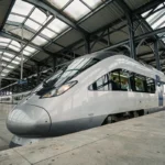 Train électrique grande vitesse entrant en gare moderne avec architecture en acier et verre, tendances transport ferroviaire innovant